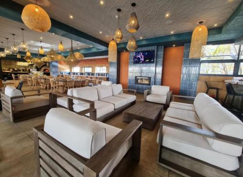 a bar with white couches and a restaurant at Cozy Pretoria Apartment with City Garden Views in Pretoria