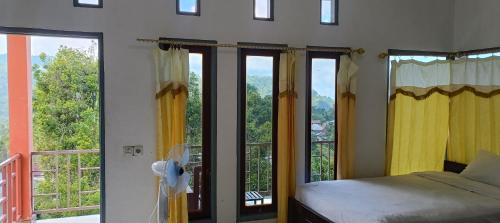 a bedroom with a bed and a balcony with windows at Moon view Bungalow's in Kelimutu