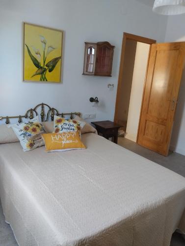a bedroom with a large white bed and a wooden door at Casa El Valle Verde Granada in Lecrin
