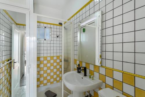 a bathroom with yellow and white tiled walls and a sink at Los Adejo vacacional in Moya