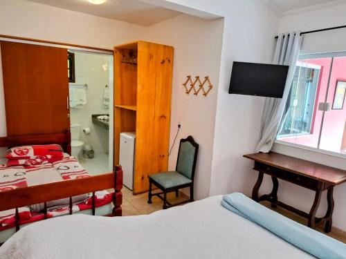 a bedroom with a bed and a desk and a table at Vila Palmar Hospedagem in Vassouras