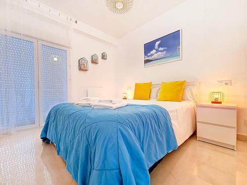 Schlafzimmer mit einem Bett mit blauer Bettwäsche und gelben Kissen in der Unterkunft Mar de Cristal Apartment - 6410 in Mar de Cristal
