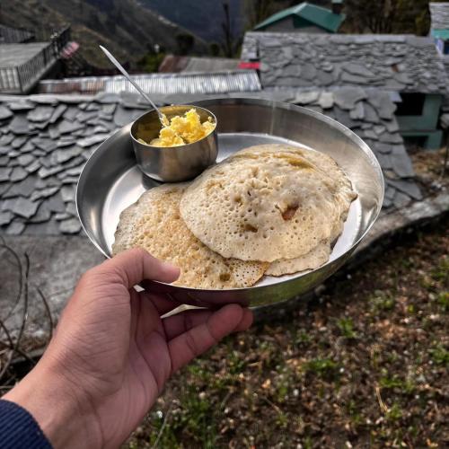 a person holding a plate with a plate of food at Sunlight Homestay Mohana in Chakrāta