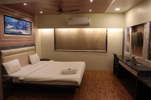 Un dormitorio con una cama blanca y un televisor. en Hotel Vinyasa Residency, en Bhayandar