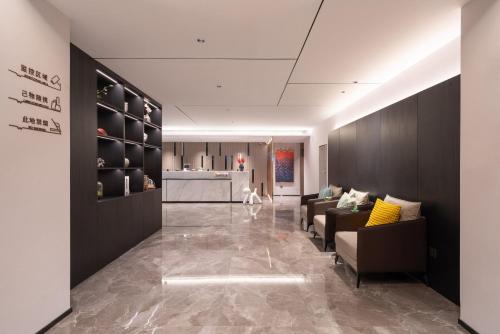 a living room with couches and a kitchen at 沃德smart酒店济南CBD化纤厂路店 in Jinan