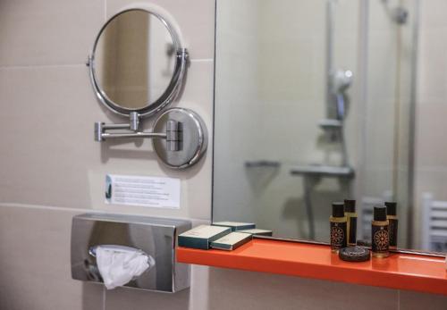 a bathroom with a mirror and a shelf with cosmetics at Hôtel CASABELLA Cannes Mouans Sartoux in Mouans-Sartoux