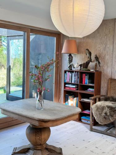 a room with a table with a vase with flowers on it at Seaside holiday home in Grenå