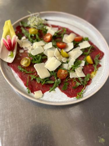 a plate of food with cheese and vegetables on a table at Logis Hôtel & Restaurant Les Perce-Neige in Bonnétage