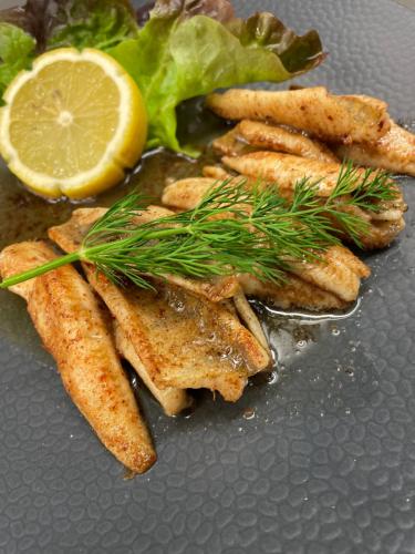 a plate of food with french fries and a lemon at Logis Hôtel & Restaurant Les Perce-Neige in Bonnétage