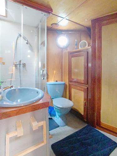 La salle de bains est pourvue d'une baignoire bleue et de toilettes. dans l'établissement La Marquise, à Melun