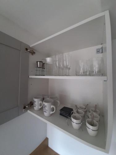 - un placard blanc avec des tasses et des tasses dans l'établissement Cassiopée - CIEL ETOILE, à Honfleur