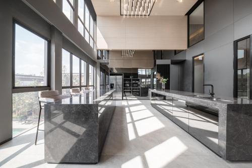 a lobby with a long counter with chairs and windows at Ramada By Wyndham Bangkok Sukhumvit 87 in Bangkok
