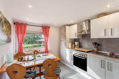 a kitchen with white cabinets and a table and chairs at Ferienwohnungen Zum Hasenbahnhof in Kirchhundem