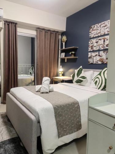 a bedroom with a large bed with blue walls at Simple Haven at Inspiria Davao Beside Abreeza Mall - Fully Equipped Studio in Davao City