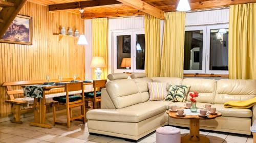 a living room with a couch and a table at Różany Ogród - dom pod lasem, z widokiem na jezioro i kominkiem, rowery, łódka, rowerek wodny in Przezmark