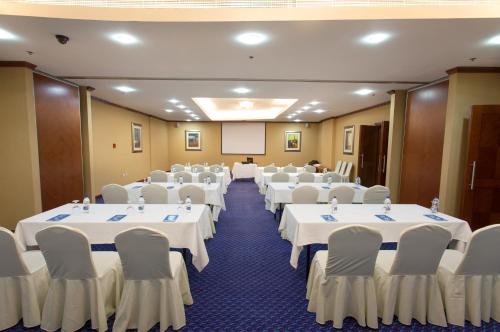 a conference room with white tables and chairs and a screen at Chelsea Gardens Hotel Apartment in Dubai