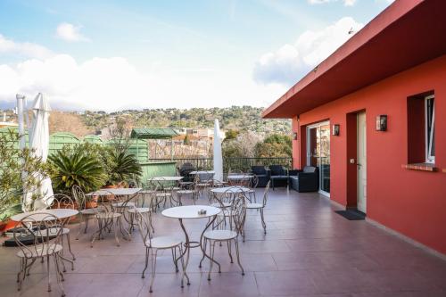 a patio with tables and chairs on a building at Hôtel CASABELLA Cannes Mouans Sartoux in Mouans-Sartoux