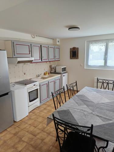 - une cuisine avec des appareils blancs, une table et des chaises dans l'établissement La Bastide, à Labastide-Saint-Pierre