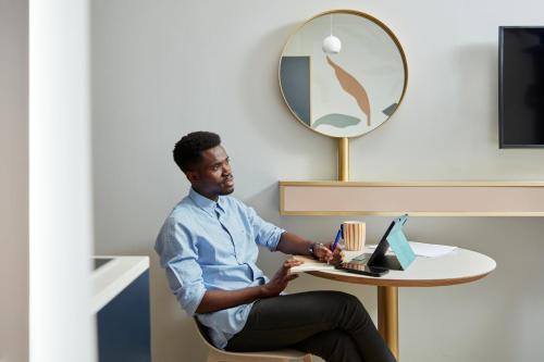 a man sitting at a table with a laptop at Adagio access Brussels Delta in Brussels