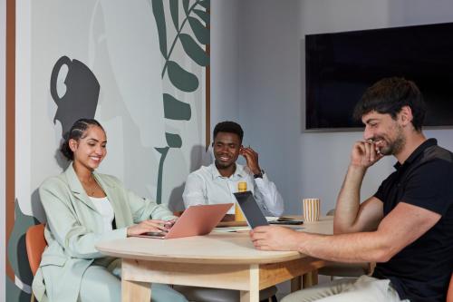 a group of three people sitting at a table with a laptop at Adagio access Brussels Delta in Brussels