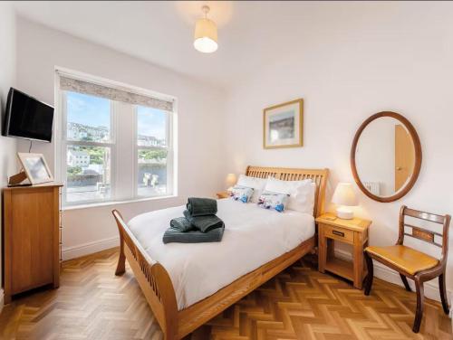una camera da letto con un letto, uno specchio e una sedia di White Horses - Seaviews a Ilfracombe