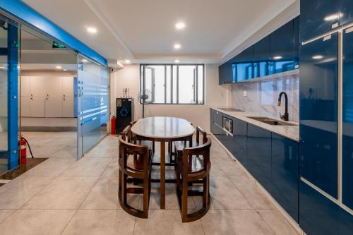 a kitchen with blue cabinets and a table and chairs at Lynn by La Doma Express in Ho Chi Minh City