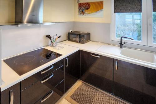 d'une cuisine avec des placards bruns, un évier et une fenêtre. dans l'établissement Mulatière View, à La Mulatière