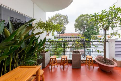a balcony with a table and chairs and trees at Lynn by La Doma Express in Ho Chi Minh City