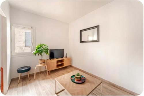 un salon avec une télévision et une table dans l'établissement L'appartement de la Roquette centre historique Arles, à Arles
