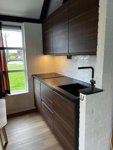 a kitchen with wooden cabinets and a sink and a window at Vakantiewoning P3F in Plombières