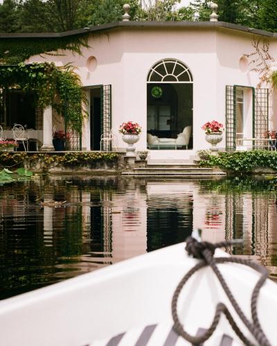 a white house with a pond in front of it at Relais La Foleia - Luxury Villa with private lake in Veruno