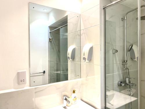 een badkamer met een douche, een spiegel en een wastafel bij KS Spacious Studio Apartment in Accra