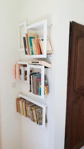 une étagère blanche sur un mur avec des livres dans l'établissement Mas La Solarie au coeur des Cévennes avec accès privé à la rivière, à Thoiras