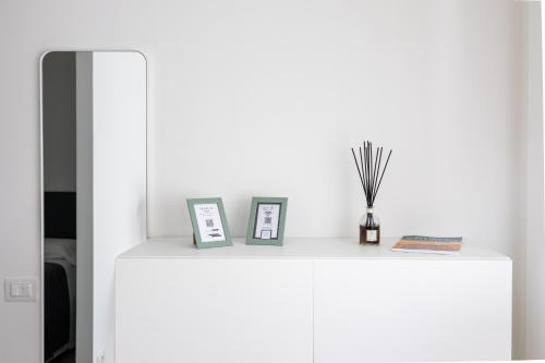 a white cabinet with two pictures and a vase on it at Amarena Vacanze in Porto Recanati