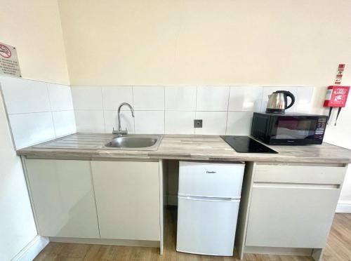 a kitchen counter with a sink and a microwave at Crompton Guest House in Hounslow