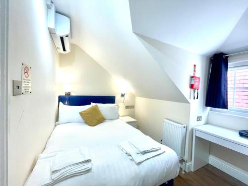 a bedroom with a white bed with a blue headboard at Crompton Guest House in Hounslow