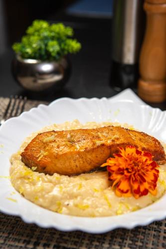 a plate of food with a piece of meat and a flower at Hotel Darolt Criciúma in Criciúma