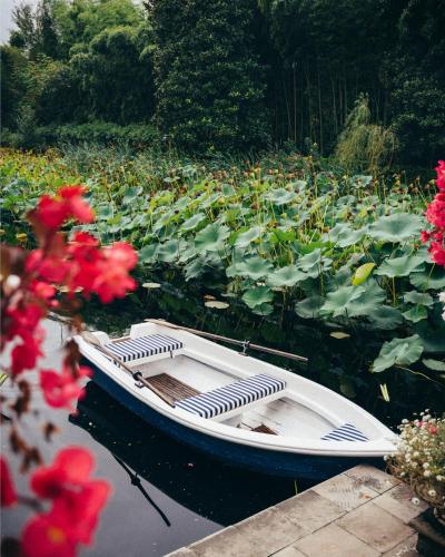 a boat sitting in the water next to flowers at Relais La Foleia - Luxury Villa with private lake in Veruno