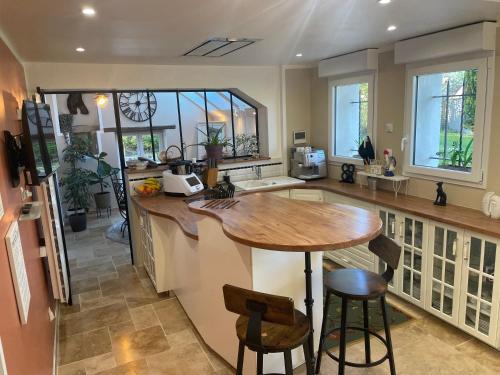 une cuisine avec un comptoir en bois et un îlot de cuisine dans l'établissement Maison avec piscine 24heures du Mans, à Yvré-lʼÉvêque