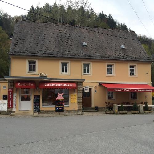 a building with a store with red signs in front of it at Pension Hönel-Hof Bad Schandau in Bad Schandau
