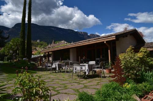 a patio with tables and chairs in front of a building at Angerburg Blumenhotel in Appiano sulla Strada del Vino