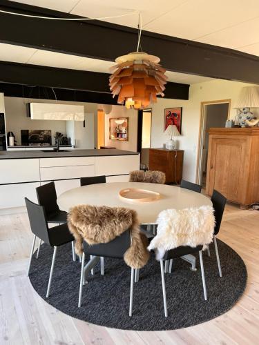 a dining room with a table and chairs with fur covered seats at Seaside holiday home in Grenå