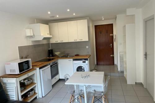 une cuisine avec des appareils blancs et une table avec des chaises dans l'établissement Appartement Lyon 8 proche métro, à Lyon