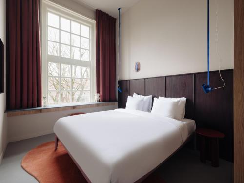 a large white bed in a room with a window at Conscious Hotel Oudegracht in Utrecht
