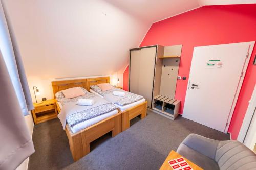 a bedroom with two beds and a red wall at Penzion Nad Lávkou in Uherský Brod