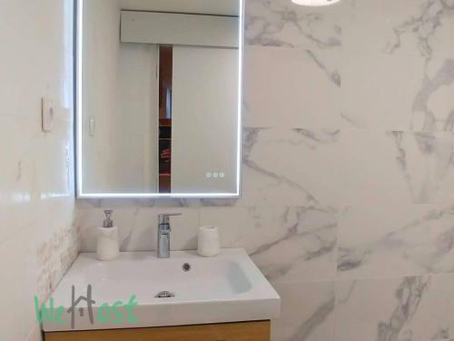 une salle de bain avec un lavabo blanc et un miroir dans l'établissement Maréchal - KP - PB - Apartment in center, à Biarritz