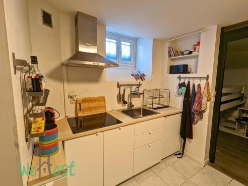 une cuisine avec des armoires blanches, un évier et une cuisinière dans l'établissement Maréchal - KP - PB - Apartment in center, à Biarritz