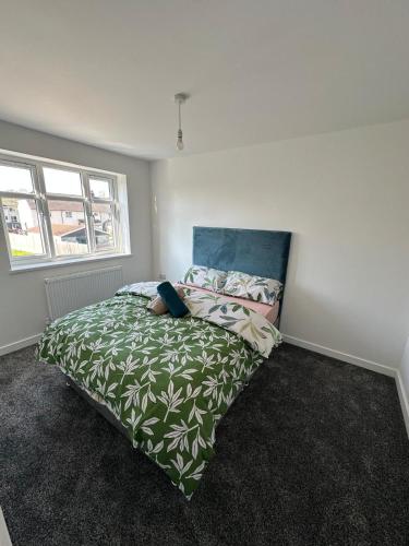 a bedroom with a bed with a green comforter at Charming and Cosy 4 bedroom House - Stockport in Bredbury