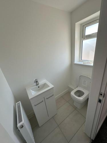 a white bathroom with a sink and a toilet at Charming and Cosy 4 bedroom House - Stockport in Bredbury