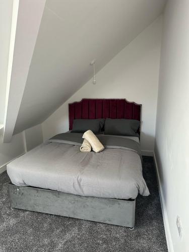a bed with a red headboard in a room at Charming and Cosy 4 bedroom House - Stockport in Bredbury